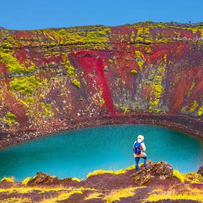 Woman standing on the edge of Kerid Volcano Crater Lake on the Golden Circle Iceland