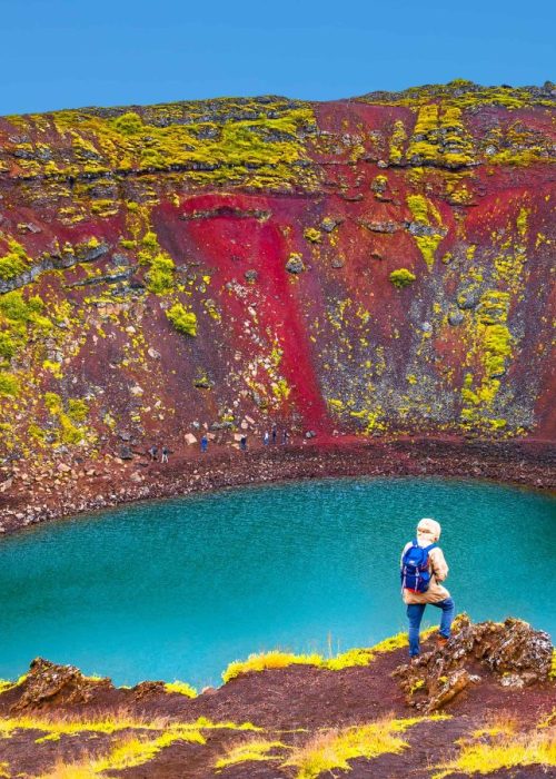 Woman standing on the edge of Kerid Volcano Crater Lake on the Golden Circle Iceland