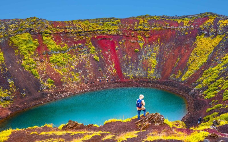 Woman standing on the edge of Kerid Volcano Crater Lake on the Golden Circle Iceland